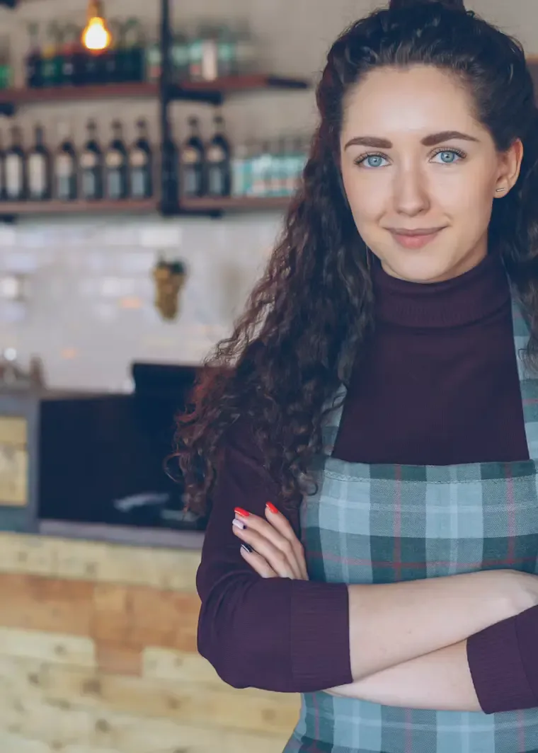 Smiling café owner standing behind the counter of her coffee shop